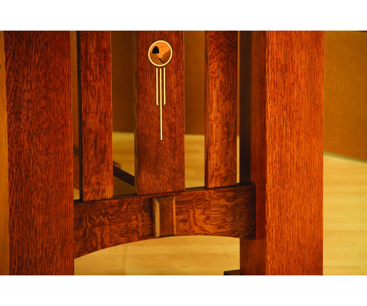 Close-up of quartersawn oak slats with an inlaid copper and light wood accent above a pegged arched stretcher