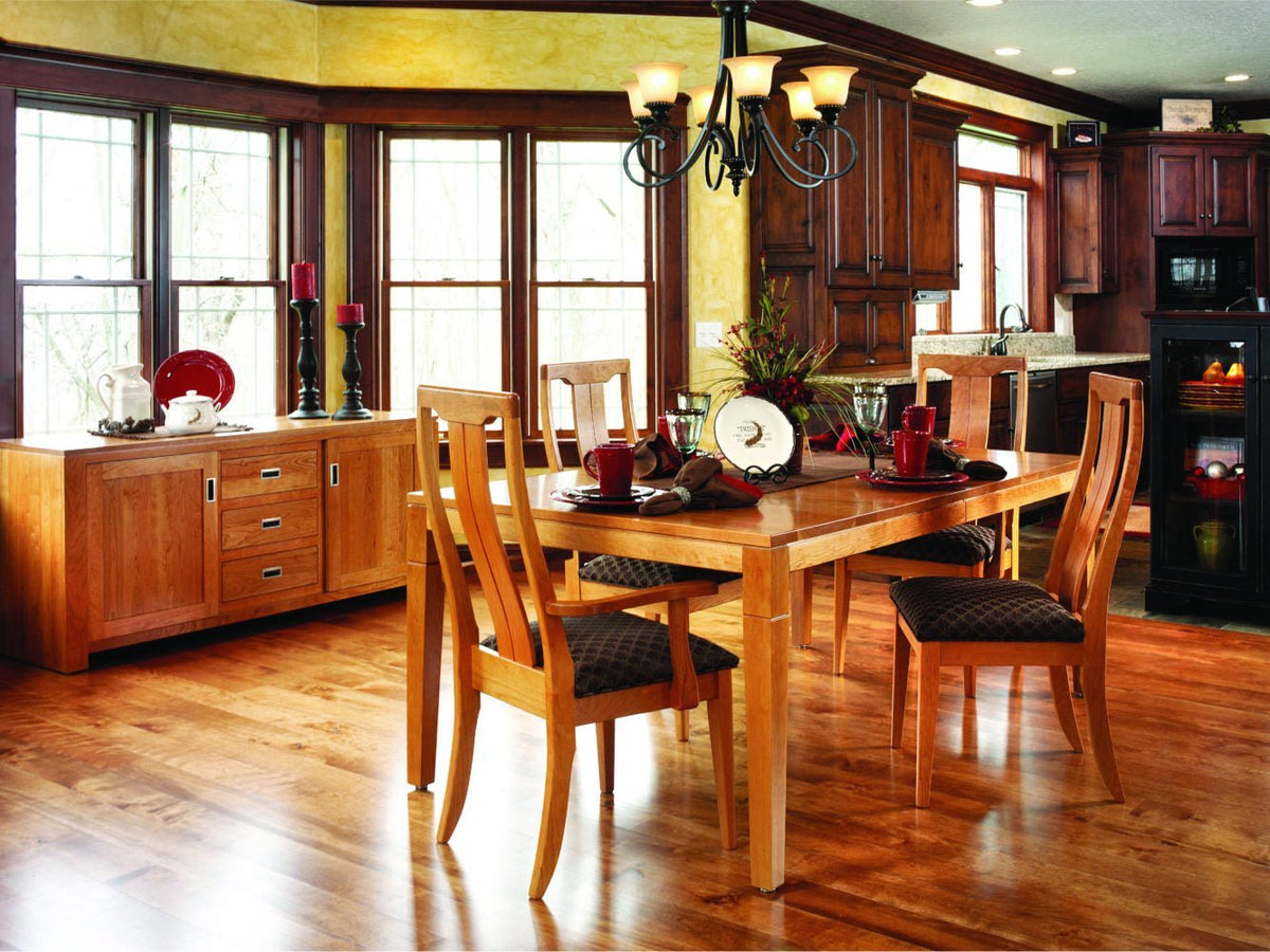 Cherry dining table with four curved slat back chairs and a matching sideboard in a warm kitchen setting