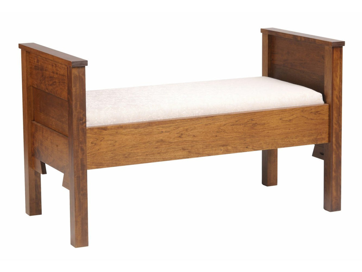 Cherry bedroom bench with paneled end posts and a cream upholstered seat on a white background