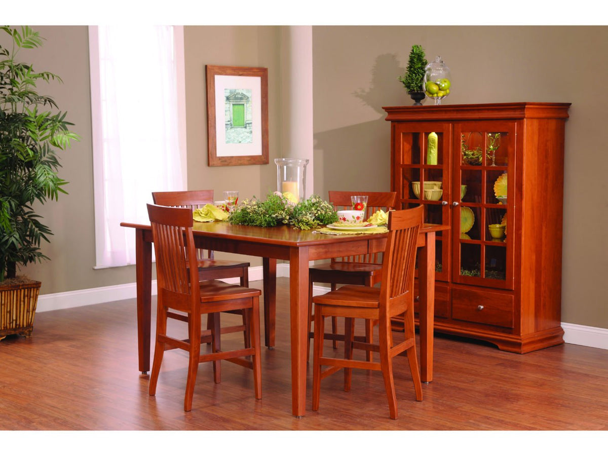 Cherry counter height table with four slat back stools and a lighted china cabinet in a bright room