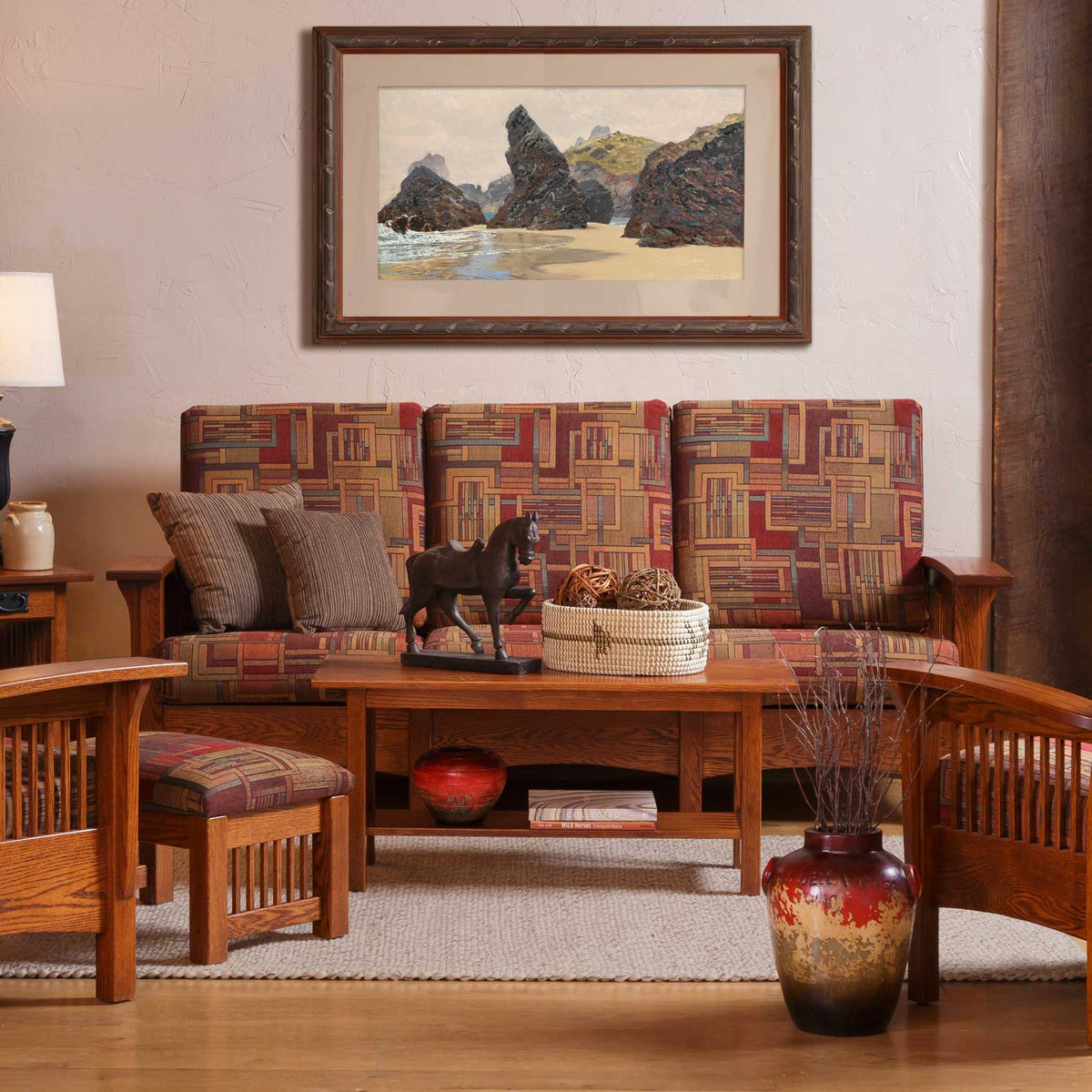 Oak Mission sofa in a red and gold patchwork print with slat sides and gray corduroy pillows under a framed print