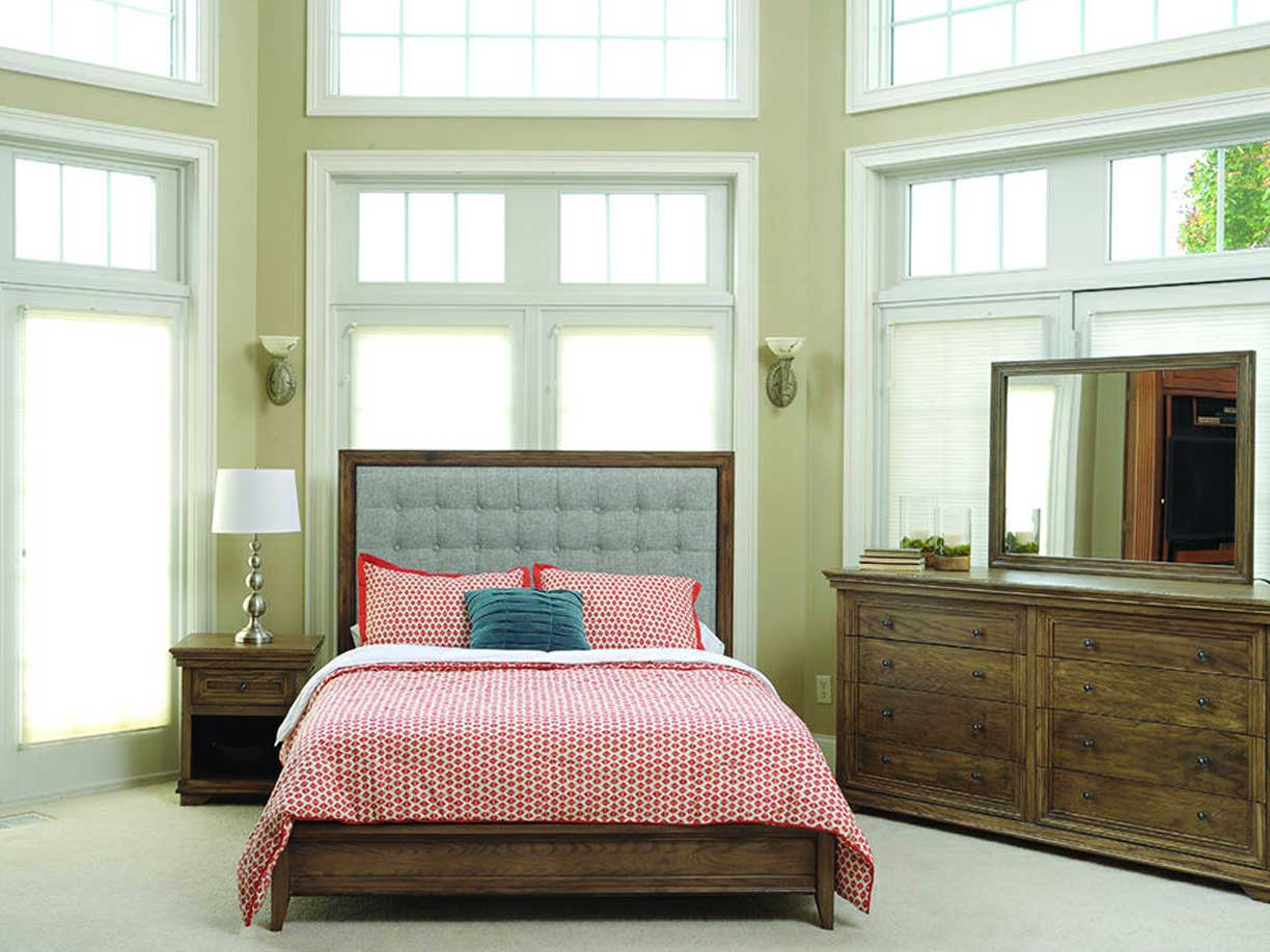 Santa Ana bed with a gray button-tufted upholstered headboard set in an oak frame, low paneled footboard and coral bedding