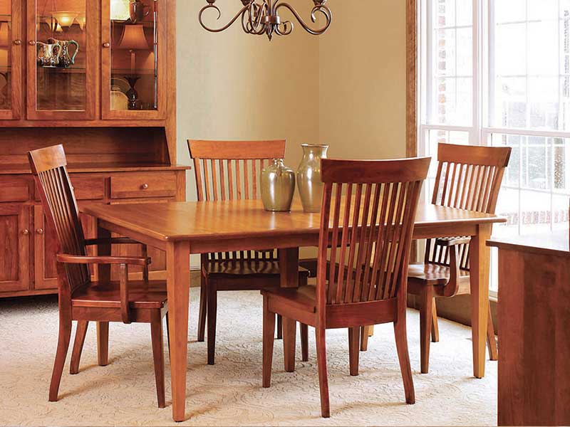 Close view of the cherry Shaker leg table set with pottery vases and surrounded by tall slat-back dining chairs