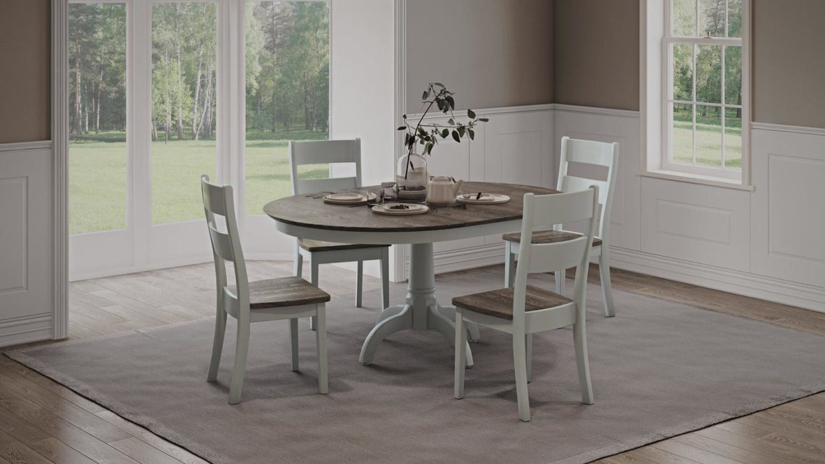 Round pedestal dining set with a gray-brown plank top, white painted base and four matching ladder back chairs in a bright dining room