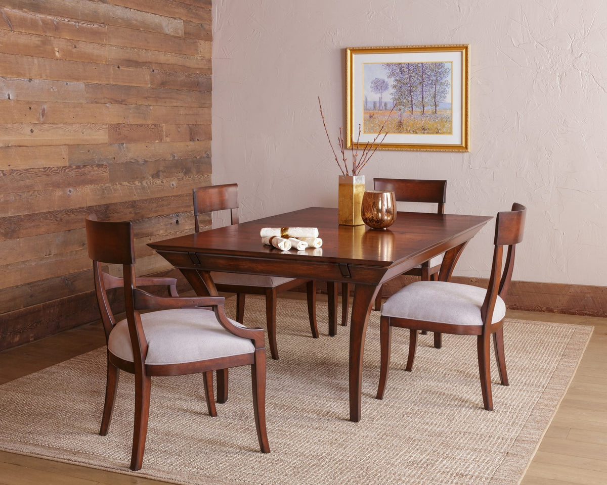 Rectangular cherry dining table with four cushioned curved back chairs styled by a reclaimed plank wall and framed art