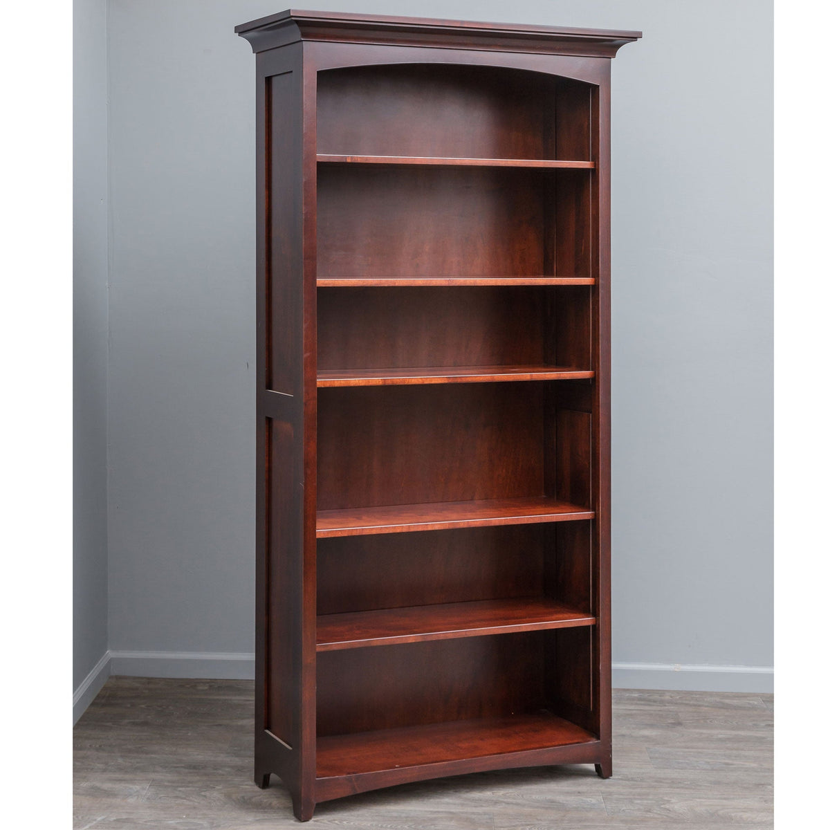 Dark cherry stained solid wood bookcase with six open shelves, arched top panel and crown molding