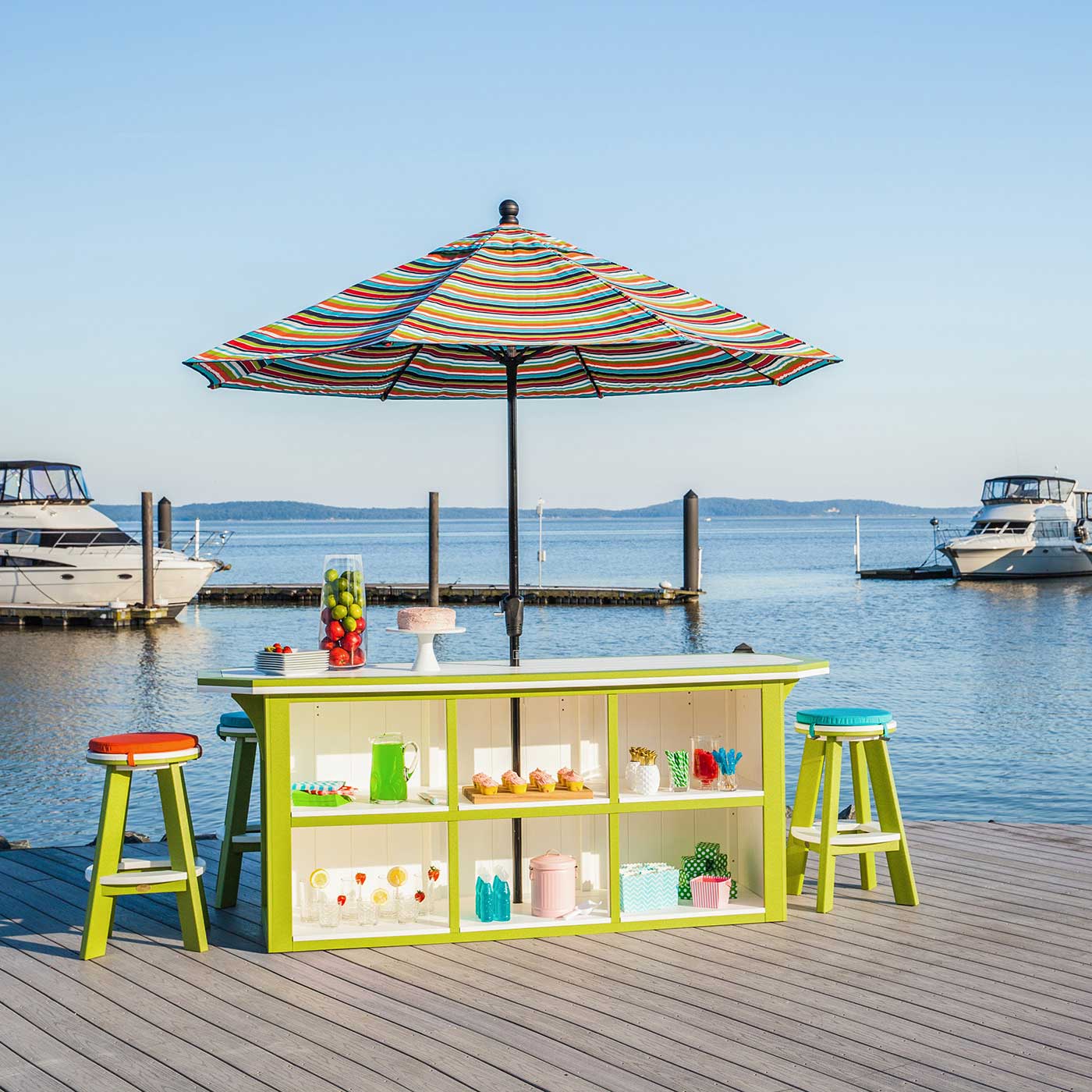 Lime green and white poly bar island with six round stools and a striped umbrella on a marina dock