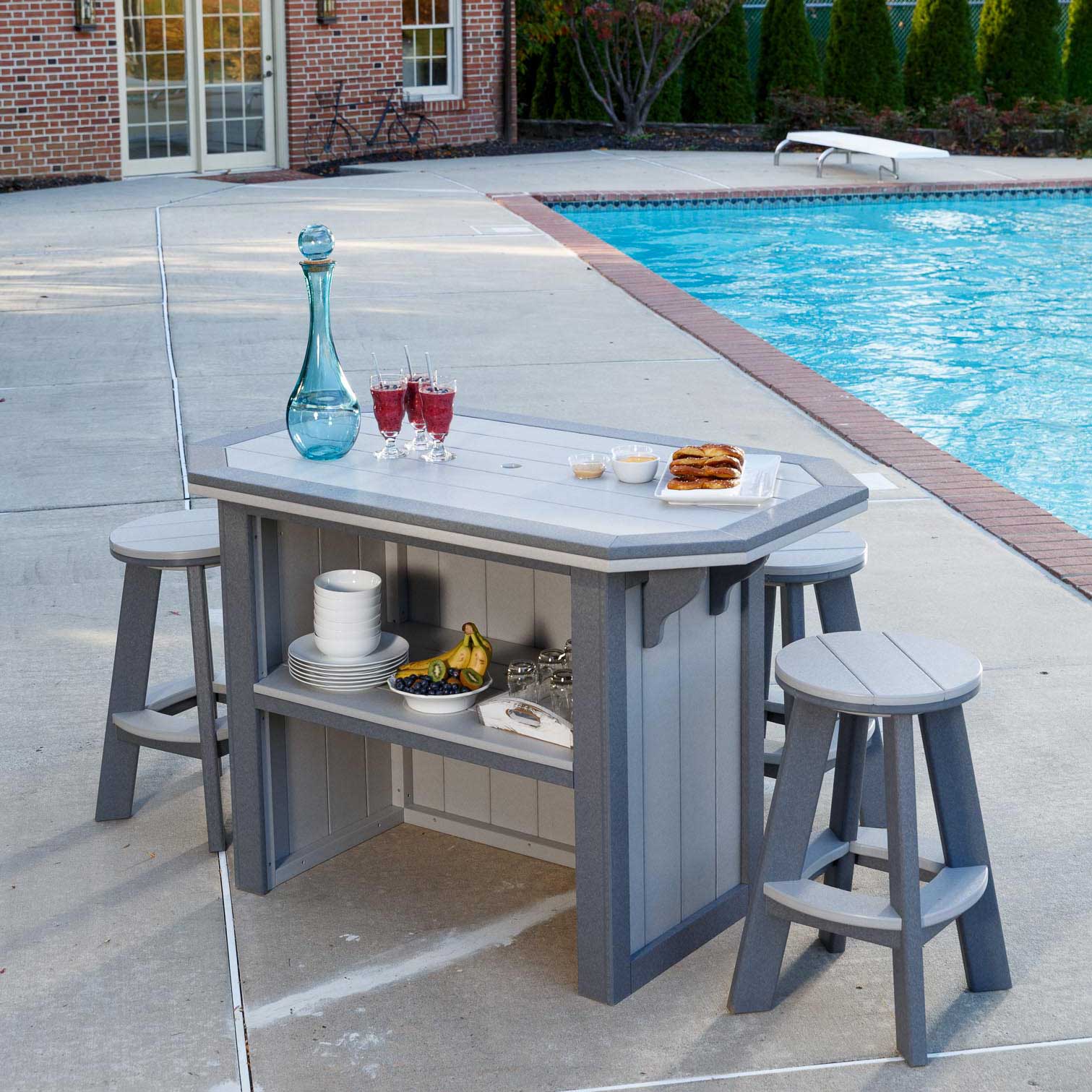 Two-tone gray poly patio bar island with four saddle stools and a blue umbrella beside a swimming pool