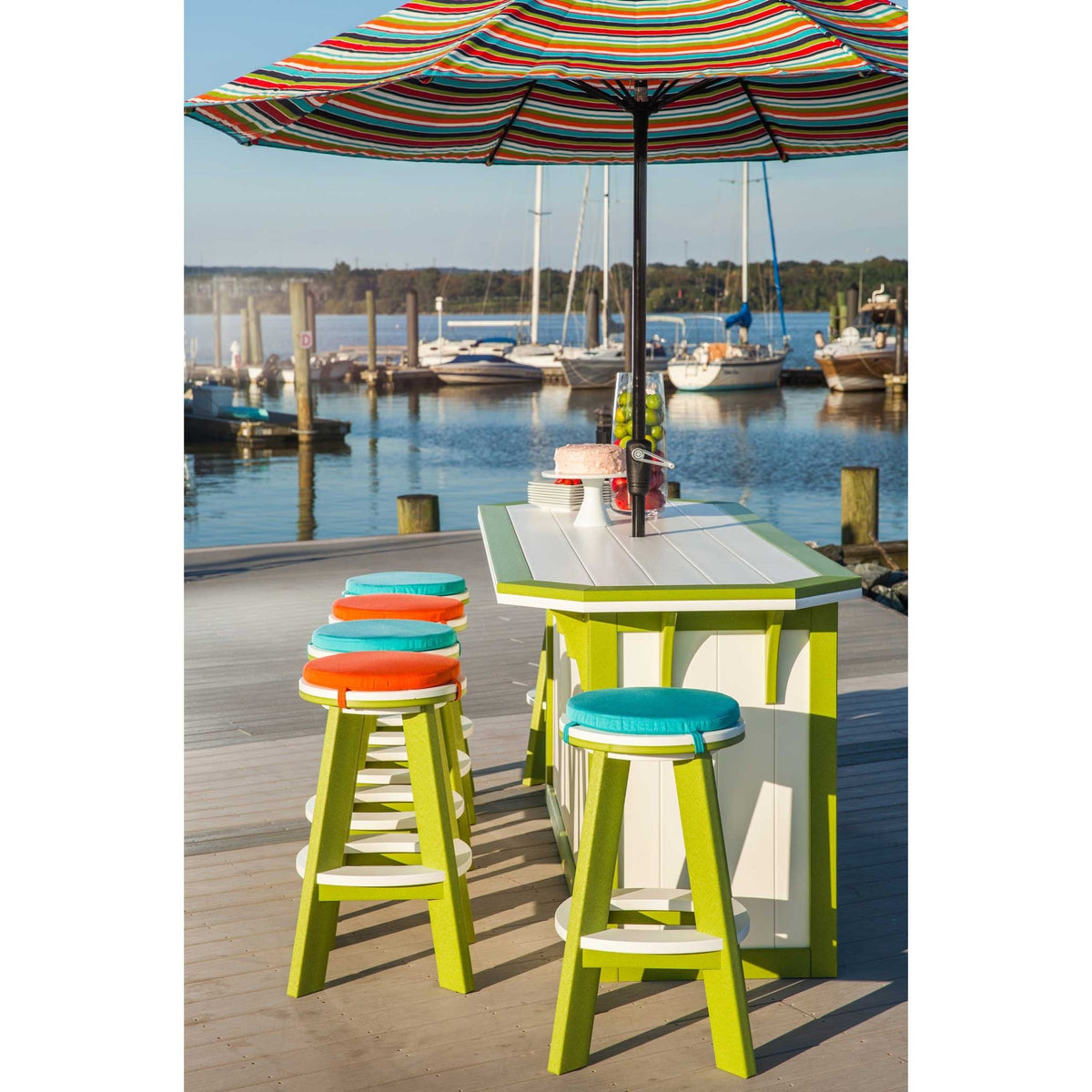 Lime green and white poly outdoor bar with swivel stools and colorful seat cushions under a striped umbrella at a boat dock