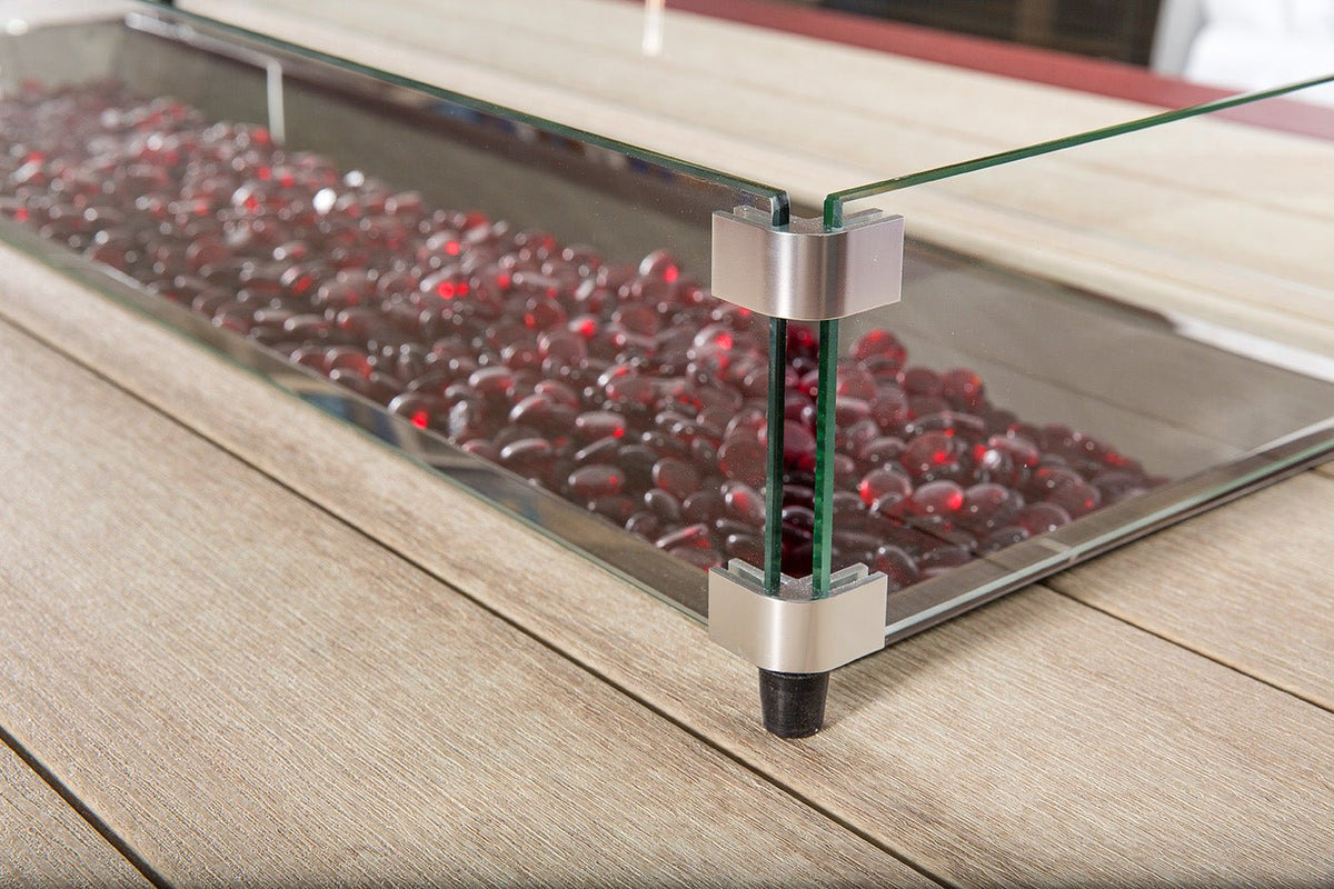 Close-up of the glass wind guard bracket and burgundy fire glass in the linear burner of a poly fire table