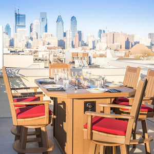 Brown poly fire pit bar table set for six with lit burner and red cushioned swivel chairs on a rooftop