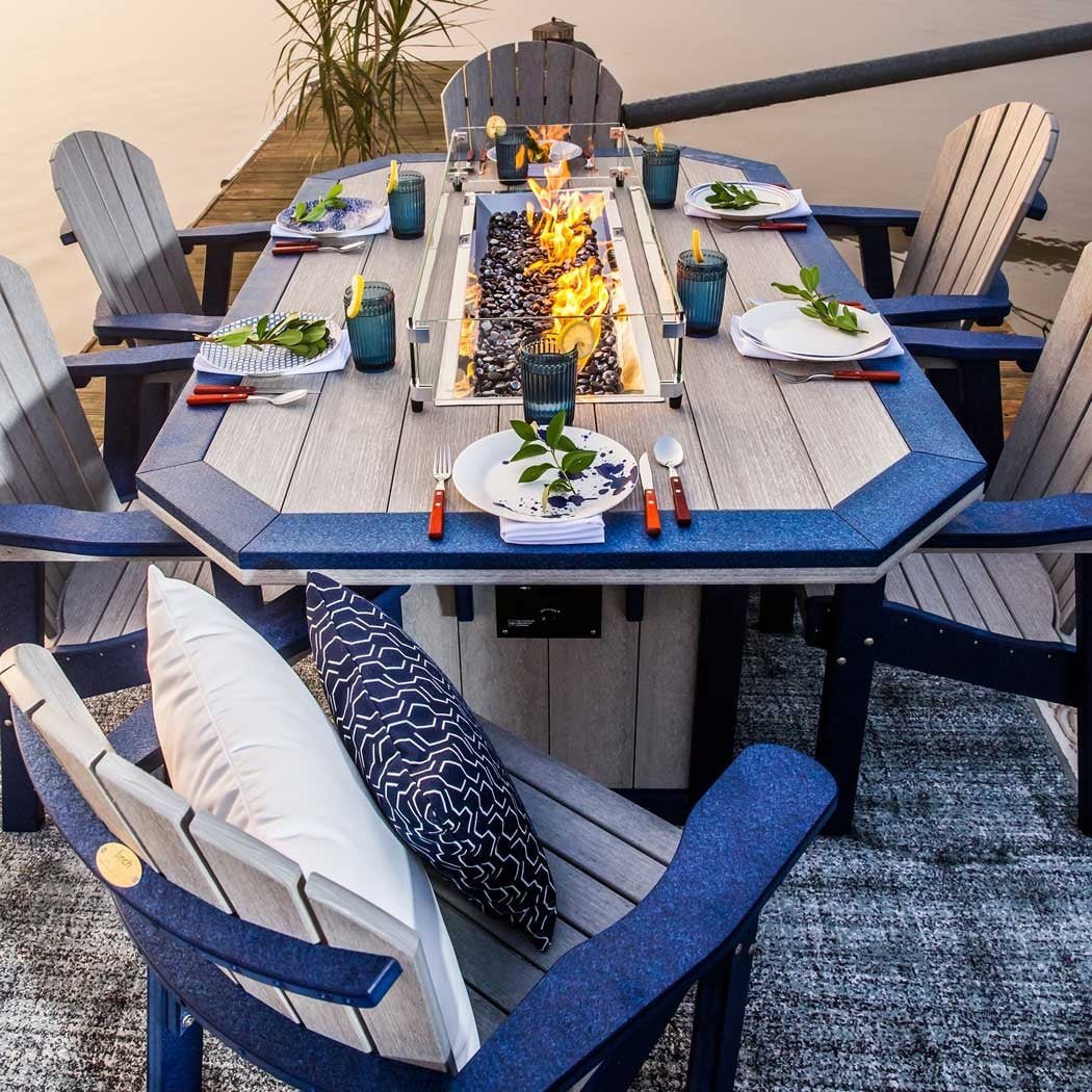Overhead view of a driftwood and navy fire dining table with center flames, place settings and pillowed chairs