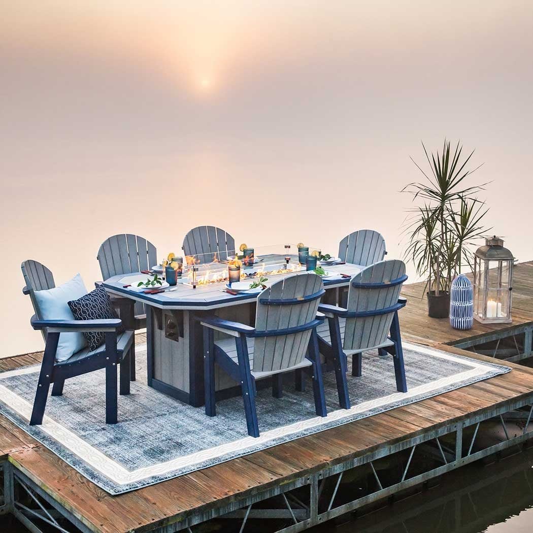 Gray and navy poly fire pit dining table for six with lanterns and a palm on a dock at sunrise