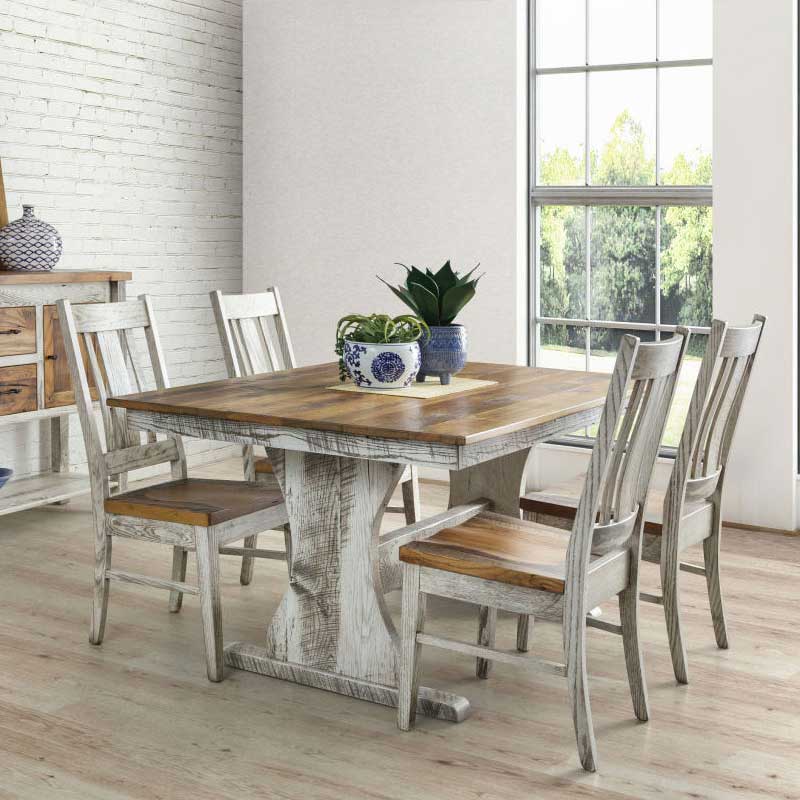 Two-tone trestle farm table with a golden reclaimed wood top and whitewashed base, surrounded by six slat back chairs