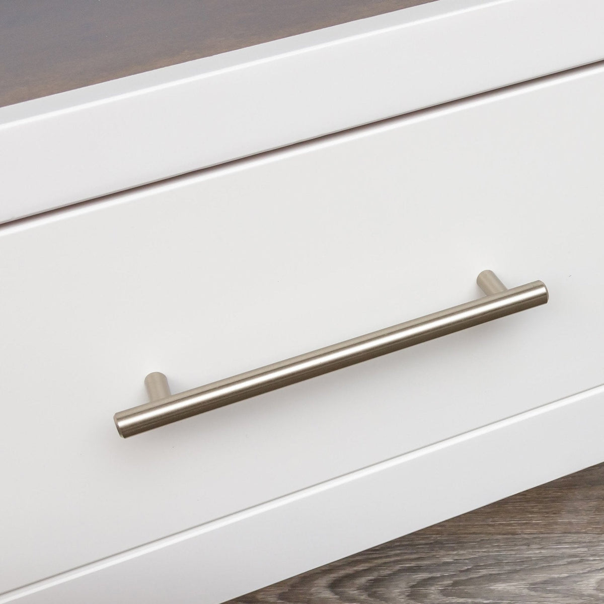 Close-up of a brushed nickel bar pull on the white painted drawer front of a wine storage server