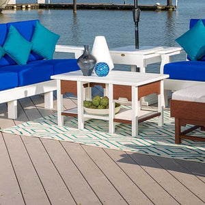 White and mahogany poly coffee table with a lower shelf on a dock, ringed by blue cushioned patio seating