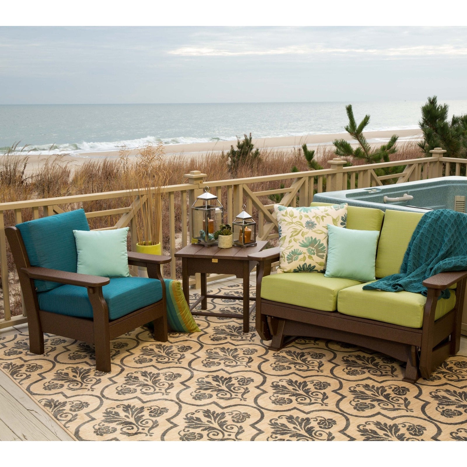 Brown poly patio chair with teal cushions, side table and green cushioned glider loveseat on an oceanfront deck