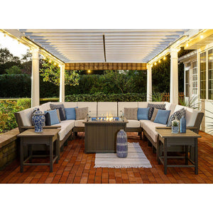 Gray poly sectional sofa set with cream cushions, blue and black pillows and end tables around a lit fire pit table