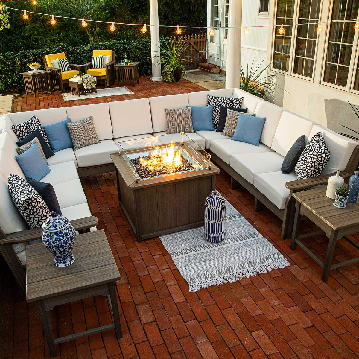 Overhead view of a nine seat U shaped patio sectional with white cushions circling a rectangular gas fire pit table