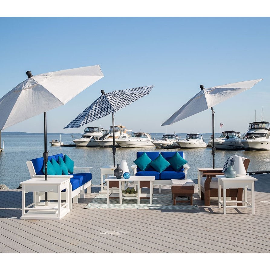 Marina dock lounge with white poly sofas, royal blue cushions, teal pillows, side tables and three market umbrellas