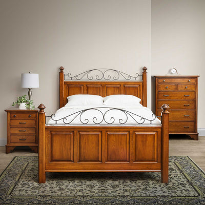 Cherry panel bed with black iron scroll accents on the headboard and footboard, flanked by chest and nightstand