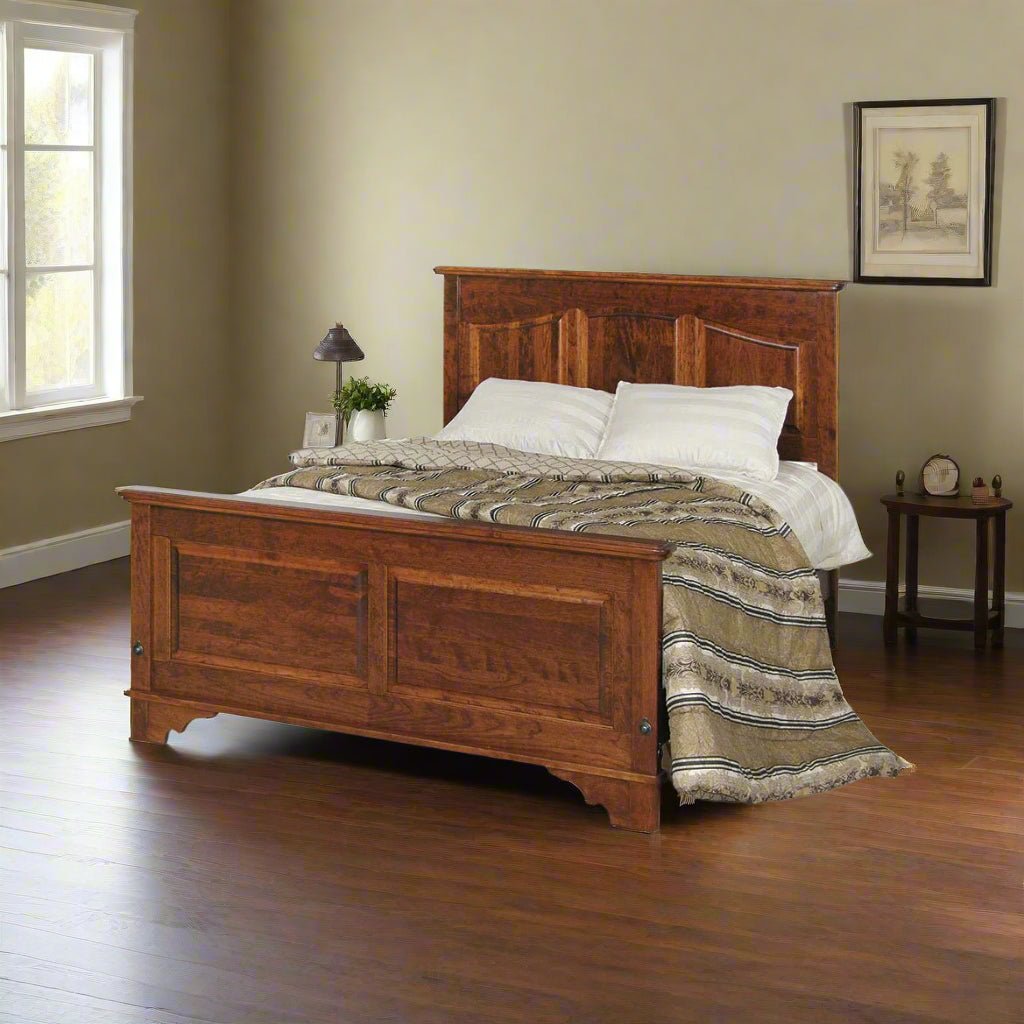 Cherry panel bed with arched headboard and paneled footboard styled with striped bedding by a window