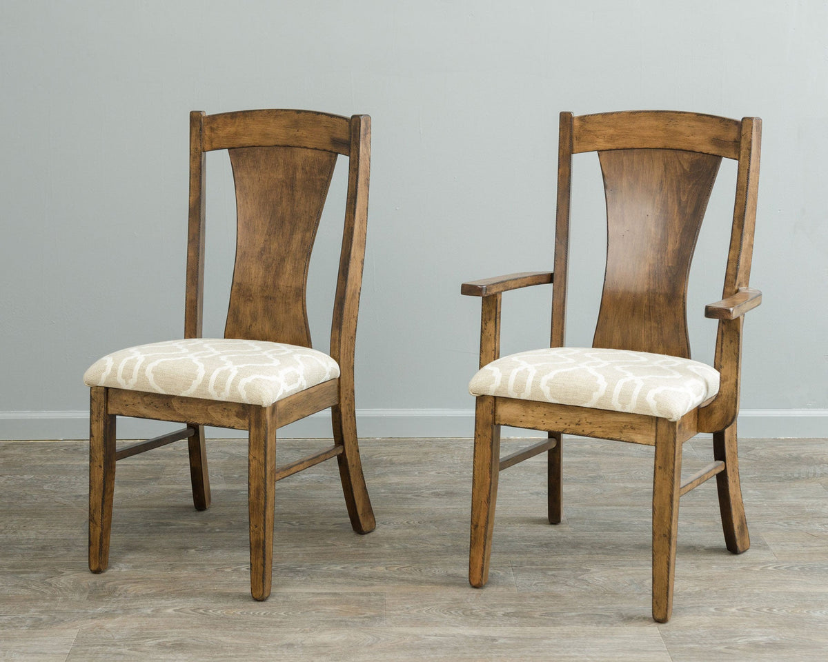 Rustic side chair and matching arm chair with hourglass back panels and cream patterned cushions against a gray wall
