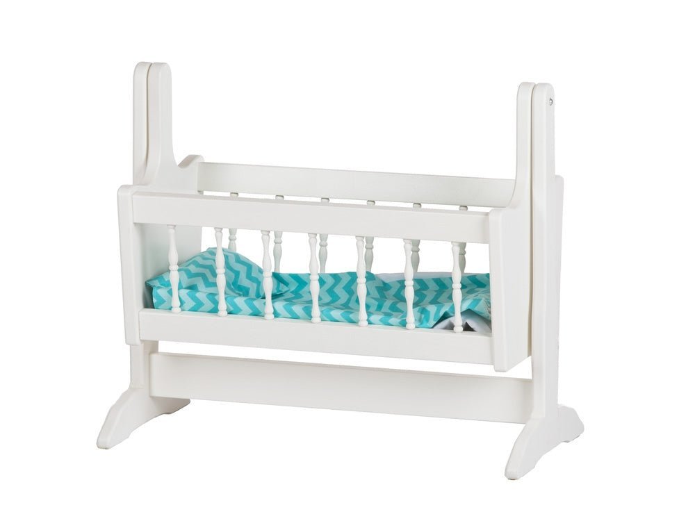 White painted swinging doll cradle with turned spindle sides, a chevron print mattress and a freestanding rocking frame
