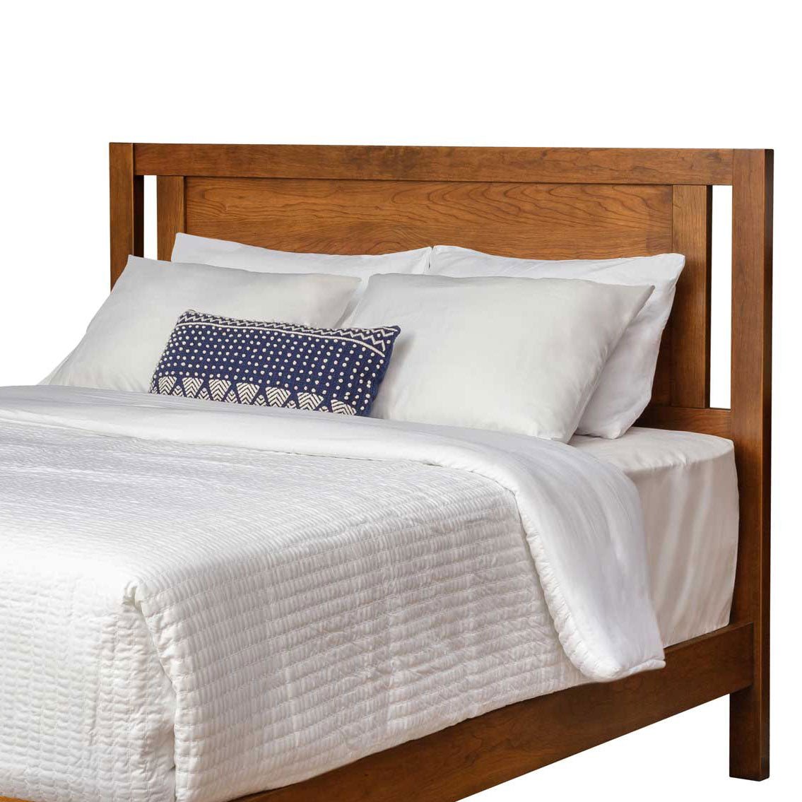 Open panel headboard only in medium brown wood, framed with squared posts behind white pillows and a navy accent