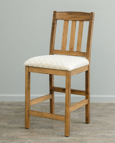 Rustic maple counter stool with three back slats and a cream geometric patterned upholstered seat