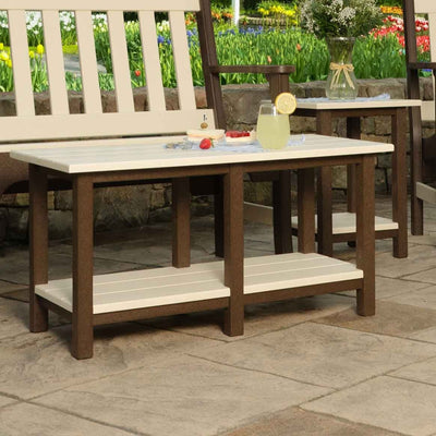 Two tone brown and ivory poly patio coffee table with a lower slat shelf on a stamped concrete patio
