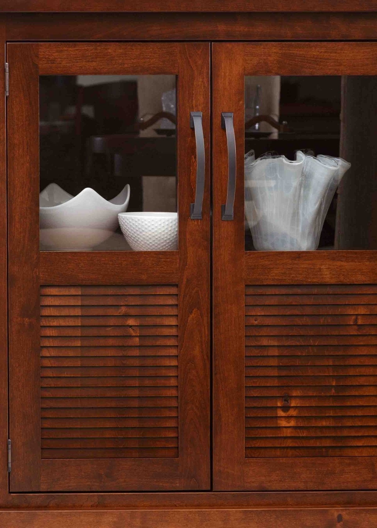Close-up of cherry buffet doors showing clear glass panels, finely louvered lower slats and dark bronze arched handles