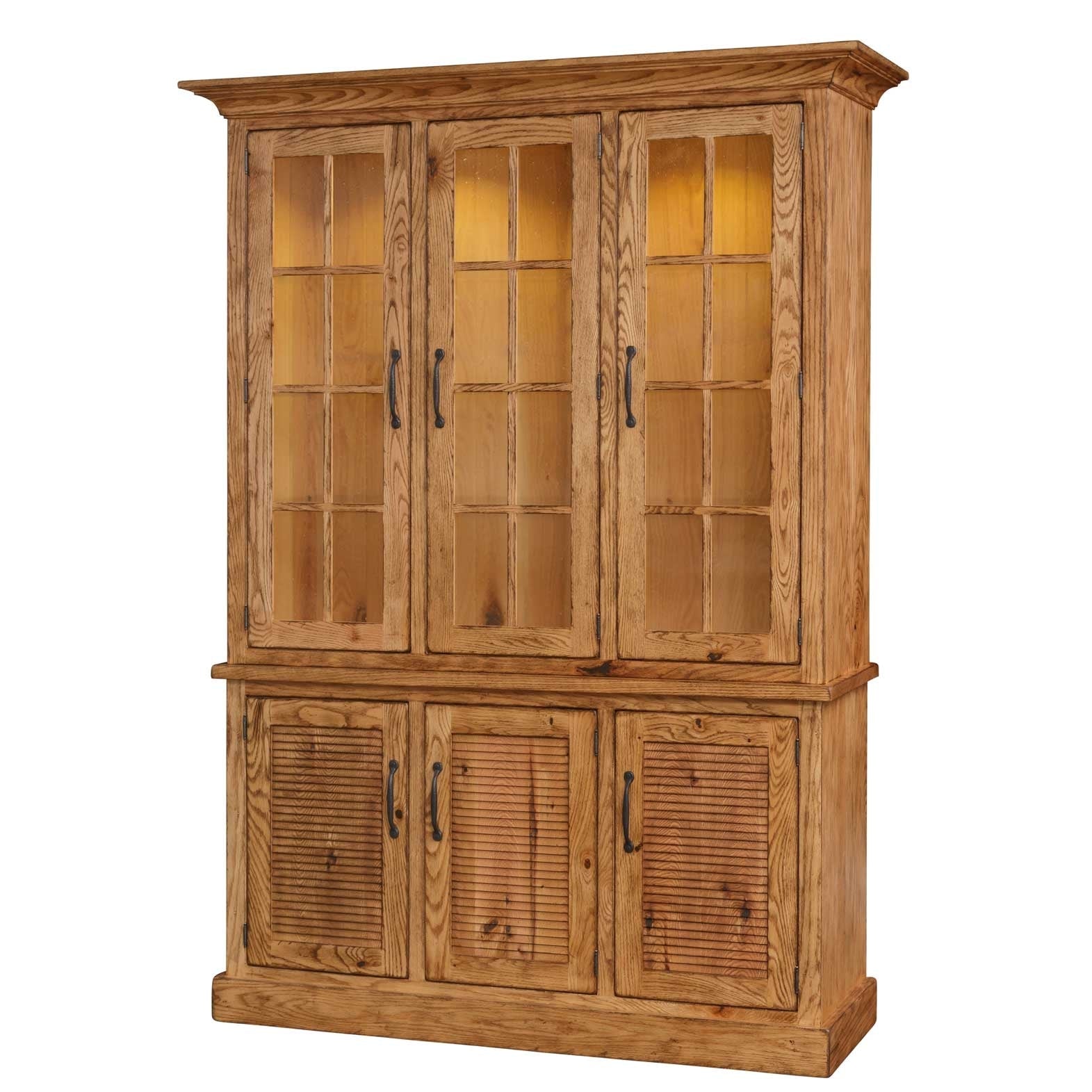 Natural oak three-door china cabinet with lit nine-pane glass doors over louvered base doors in a brick loft