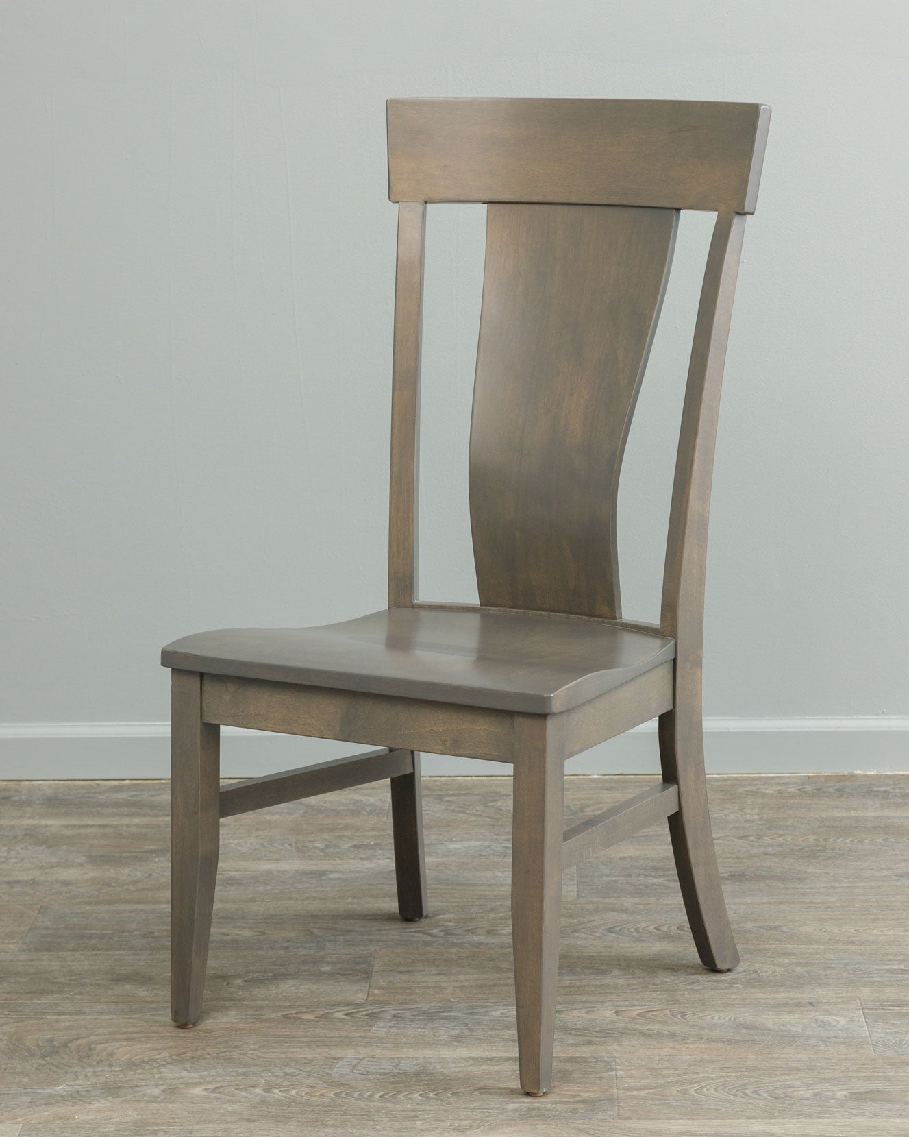 Gray stained lumbar dining chair with shaped solid back panel, flared crest rail and contoured saddle seat on wood flooring
