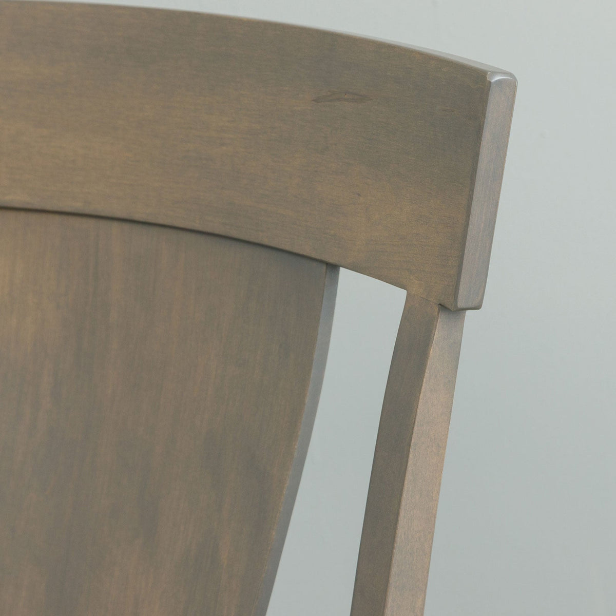 Close-up of the gray dining chair crest rail showing the flared top edge and joint where the back post meets it