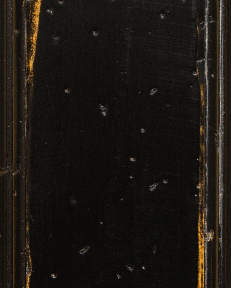 Black Antiquity paint sample with heavy distressing, nail holes and gold wood showing at the edges