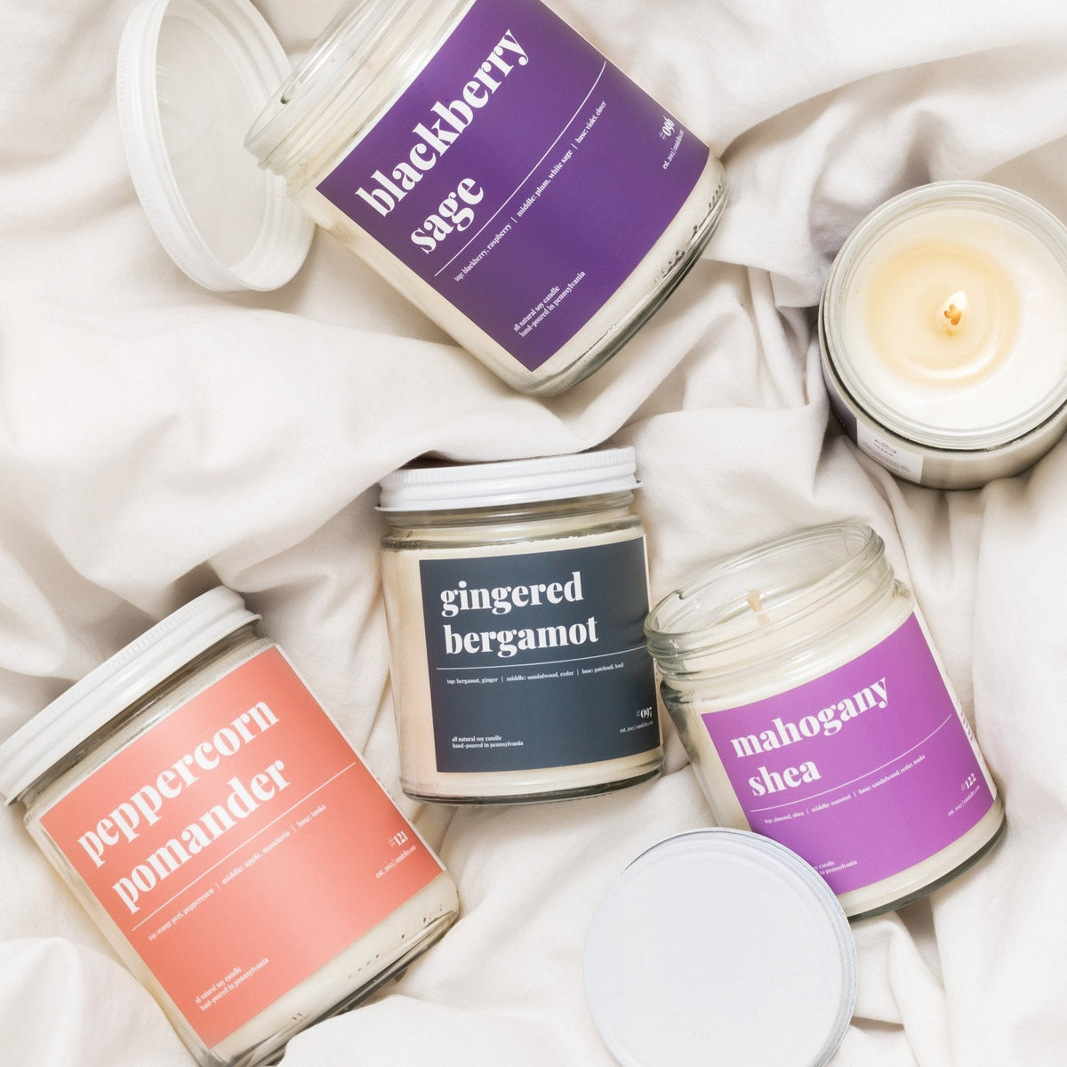Blackberry sage candle grouped with peppercorn pomander, gingered bergamot and mahogany shea jars on white linen
