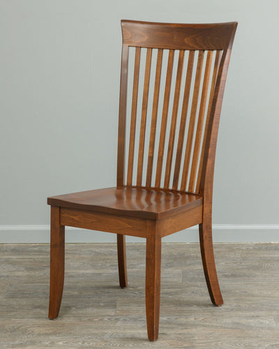 Front view of a brown maple dining chair with tall vertical slat back, curved crest rail and scooped saddle seat