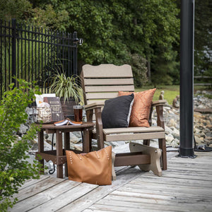 Weatherwood and brown poly curve back glider chair on a deck with pillows and a matching round side table
