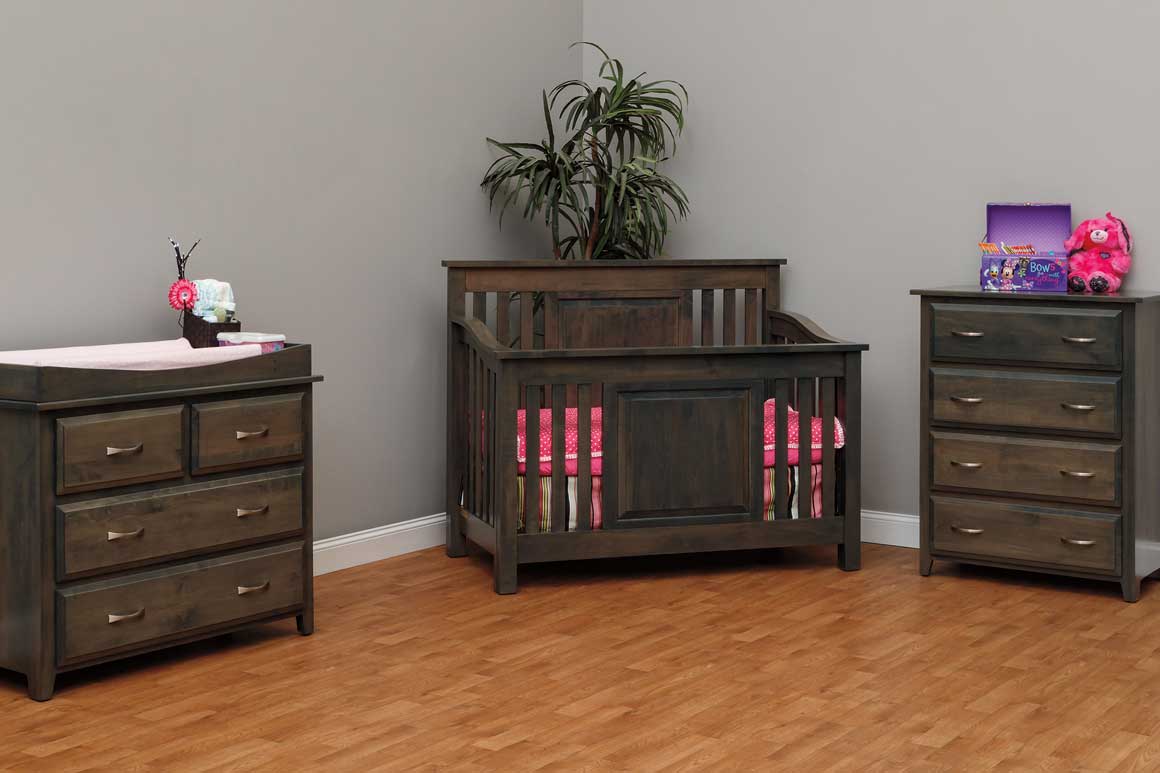 Charcoal gray Darlington crib with mission slat sides and a raised panel front, pink bedding, beside a matching chest