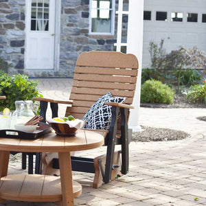 Cedar and black poly glider chair with a black and white pillow beside a round table of lemonade on pavers