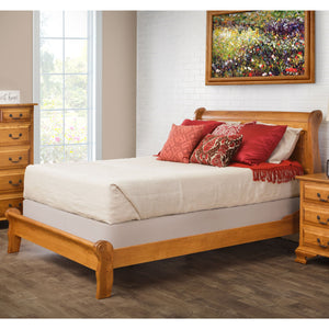 Honey oak sleigh bed with a low curved footboard, styled with red pillows in a white brick bedroom