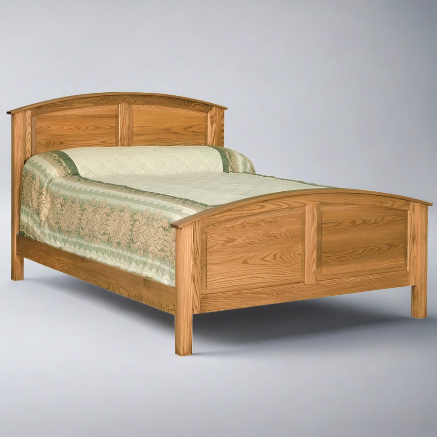 Curved raised panel oak bed with arched headboard and footboard panels and a sage floral coverlet