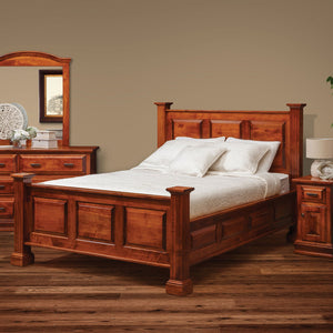 Deluxe raised panel bed in cherry-toned wood with square posts and three-panel headboard in a styled bedroom
