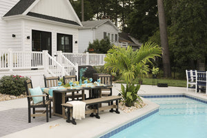 Weatherwood and black poly dining table with matching bench and chairs poolside at a white farmhouse