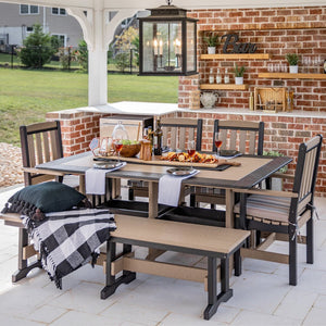 Weatherwood and black poly dining table with four chairs and two benches set for dinner in an outdoor bar pavilion