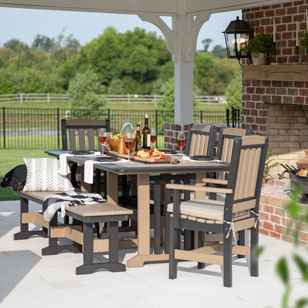 Weatherwood and gray poly dining table with cushioned chairs and a bench under a pavilion by a brick fireplace
