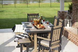 Weatherwood and gray poly rectangular dining table set with wine and charcuterie, chairs and bench on a patio
