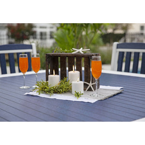 Angled view of a navy and white poly dining table with starfish decor, place mats and slat back chairs