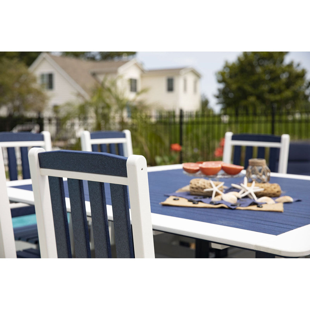 Close up of a navy and white poly patio dining table set with grapefruit halves, starfish and shells outdoors